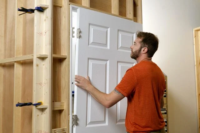 Man-lifting-white-door-from-newly-built-frame